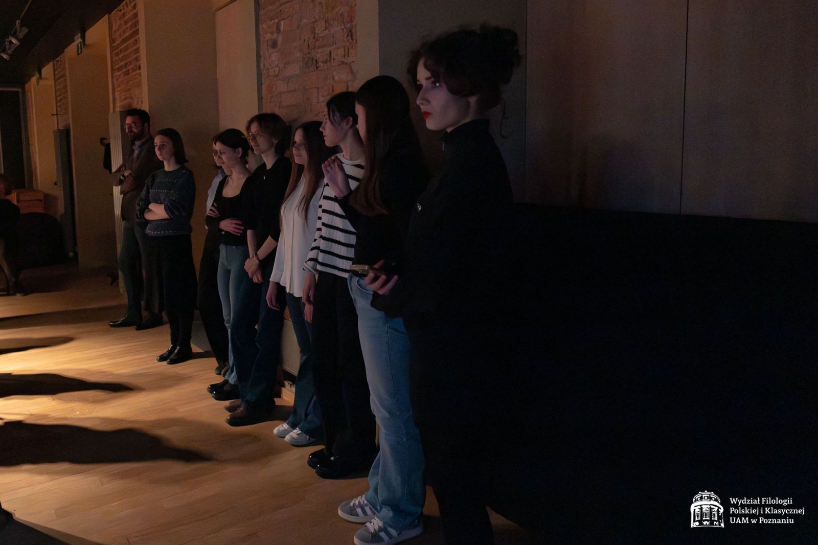 W sali teatralnej Collegium Maius pod ścianą stoją rzędem uczennice, słuchają prelekcji.