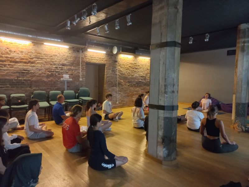 Uczestnicy szkoły letniej języka i kultury polskiej biorą udział w zajęciach jogi, które odbywają się w Sali Teatralnej Collegium Maius.