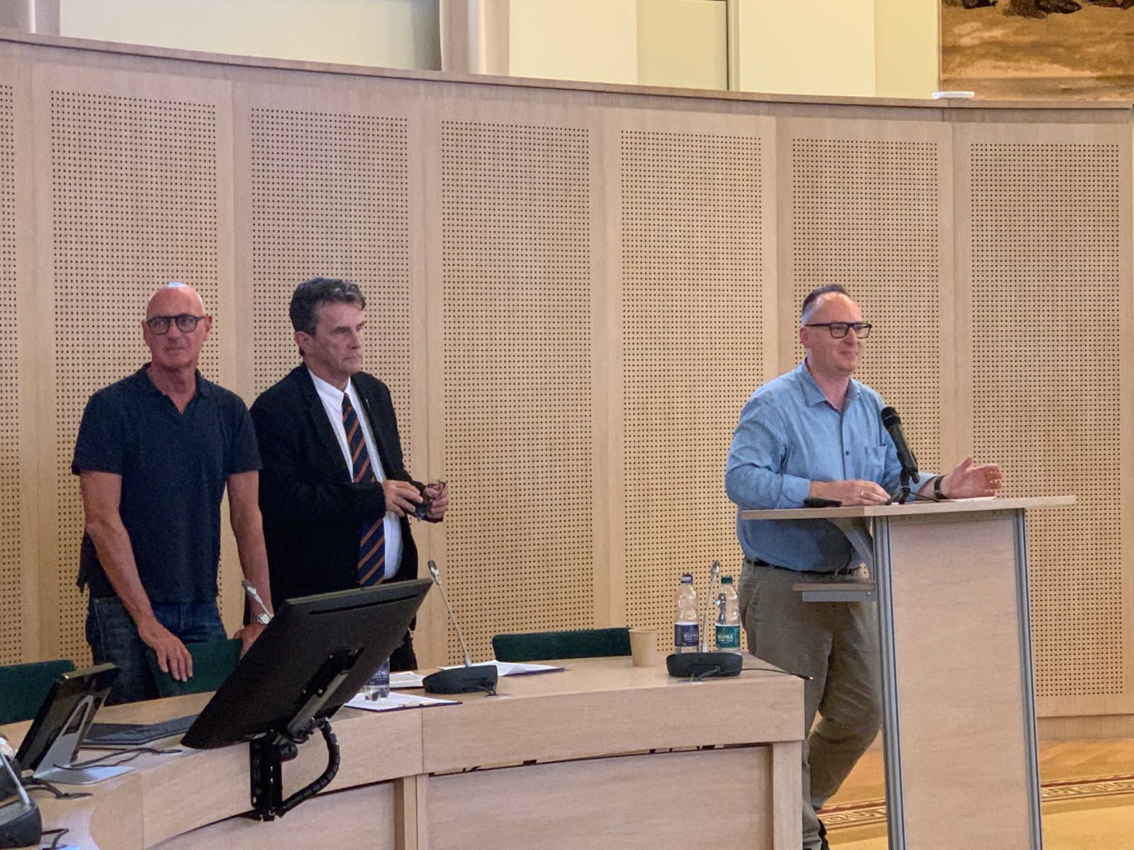 Przy mównicy w Salonie Mickiewicza stoi prof. Maciej Junkiert, obok niego dwóch zagranicznych profesorów - współorganizatorów konferencji.