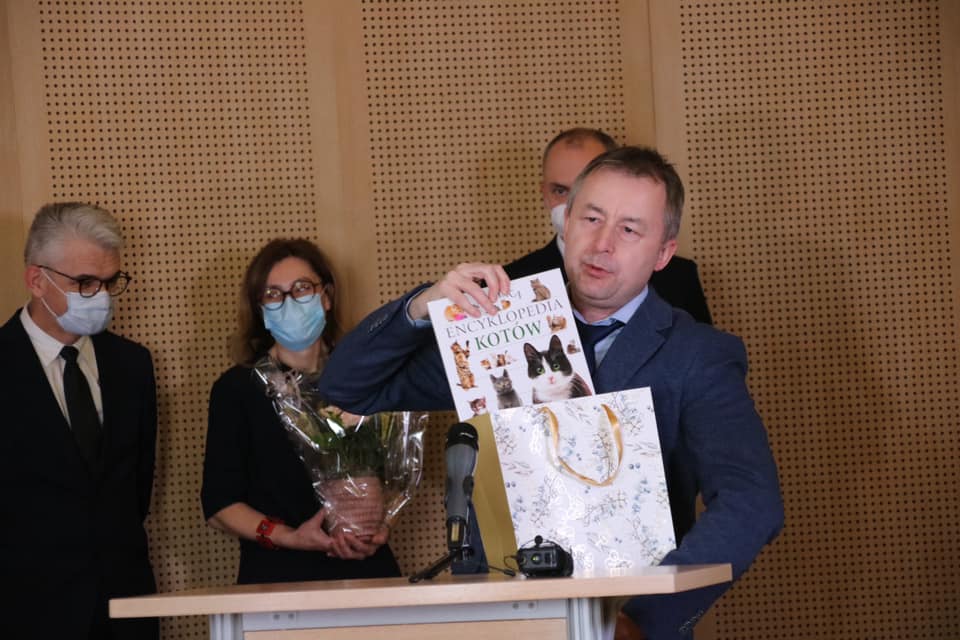 Zdjęcie z jubileuszu w Salonie Mickiewicza. Dziekan Mizerkiewicz przemawia do mikrofonu, wyciągając z torby prezentowej książkę 
