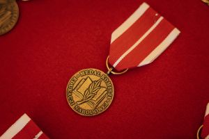 Zdjęcie przedstawia Medal Komisji Edukacji Narodowej na czerwonym tle