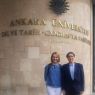 Prof. Romana Łapa wraz ze studentem z Turcji pozują przed ścianą z nazwą Uniwersytetu w Ankarze.